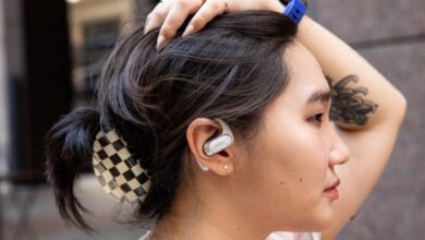 Profile of woman wearing Shokz OpenFit earbuds, hand on head.