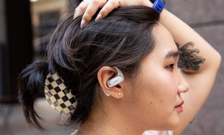 Profile of woman wearing Shokz OpenFit earbuds, hand on head.