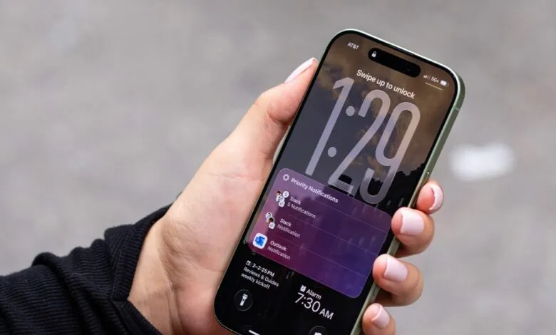Hand holding iPhone displaying lock screen with notifications.