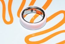 Close-up of a pink Oura Ring on a white surface with orange squiggles.