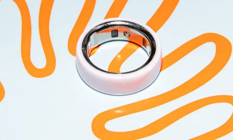 Close-up of a pink Oura Ring on a white surface with orange squiggles.