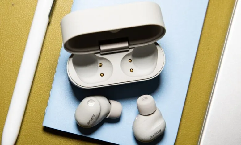 Sony WF-1000XM6 earbuds and open charging case on a blue surface.