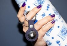 Hand holding Apple AirTag attached to a patterned water bottle.