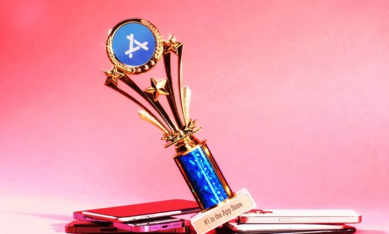 App Store trophy resting on iPhones against pink background.