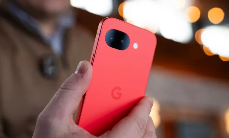 Person holding a vibrant coral-colored Google Pixel phone, showcasing its dual camera.