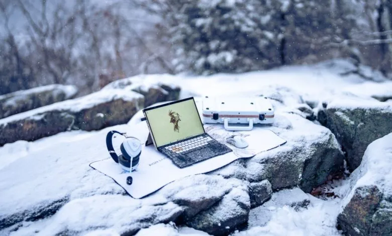Asus ROG Flow Z13 tablet, headphones, mouse, and case on snowy rocks.