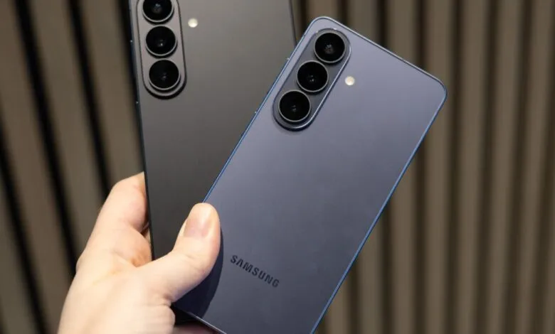 Two Samsung phones, one black, one blue, held in a person's hand.