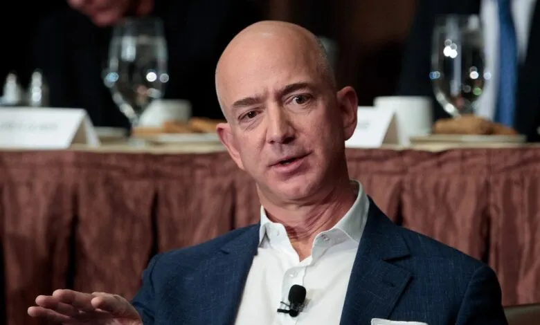 Jeff Bezos speaks at a table with a microphone.