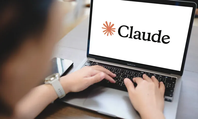 Person types on laptop displaying the Claude AI logo on a clean desk.
