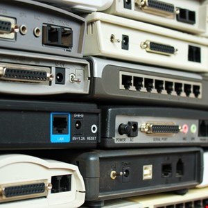 Stack of outdated modems and networking equipment showing various ports and connectors.