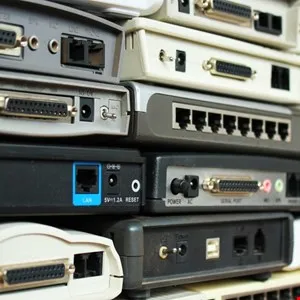 Stack of outdated modems and networking equipment showing various ports and connectors.