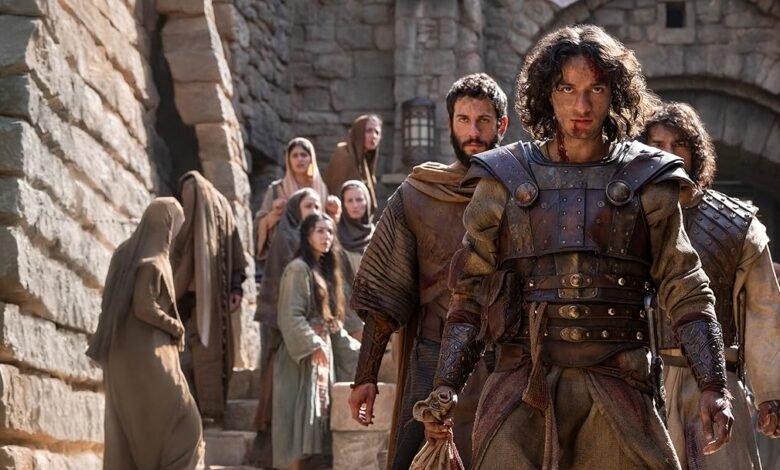 Man in armor leads a group of people through a stone village.