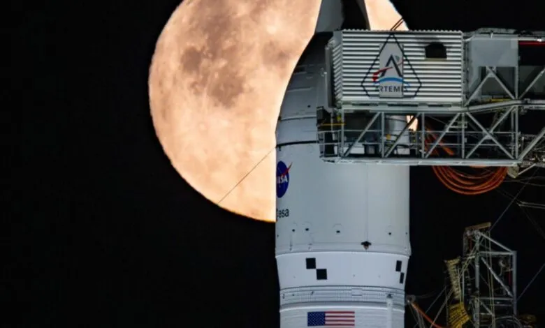 Artemis rocket on launchpad with full moon in background.