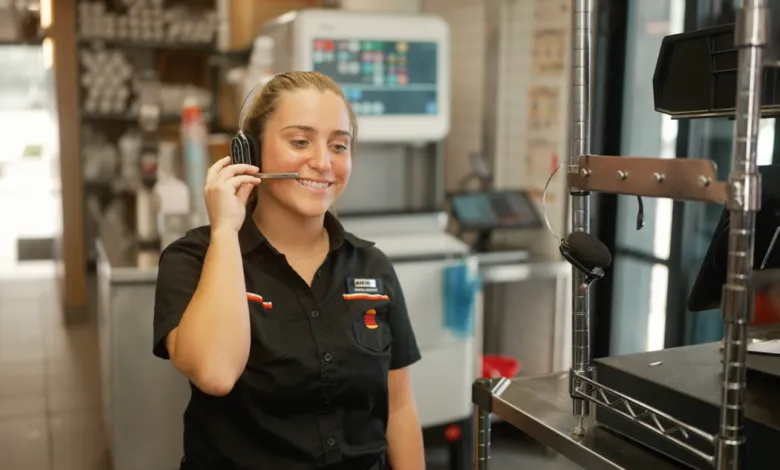 Smiling employee wearing headset at fast food restaurant.
