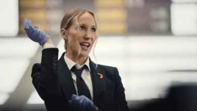 Woman in suit and gloves gestures in airport setting.