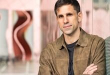 Portrait of a man in a brown jacket with arms crossed.