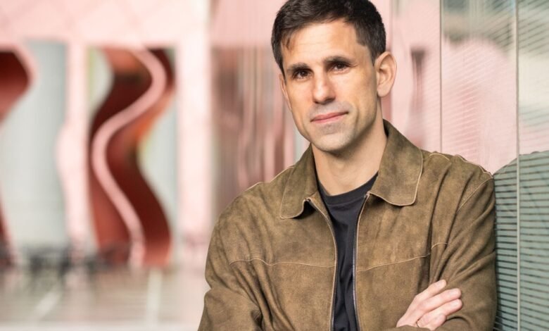 Portrait of a man in a brown jacket with arms crossed.