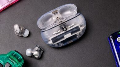 Transparent Beats earbuds and open charging case on a dark surface.