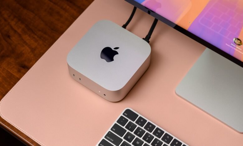 Apple Mac Mini setup with monitor and keyboard on pink desk mat.