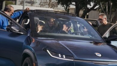 People examining a blue Fisker electric vehicle outdoors.