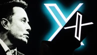 Elon Musk portrait with X logo on phone screen, dark background.