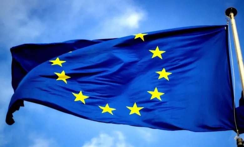 European Union flag waving against a blue sky with scattered clouds.