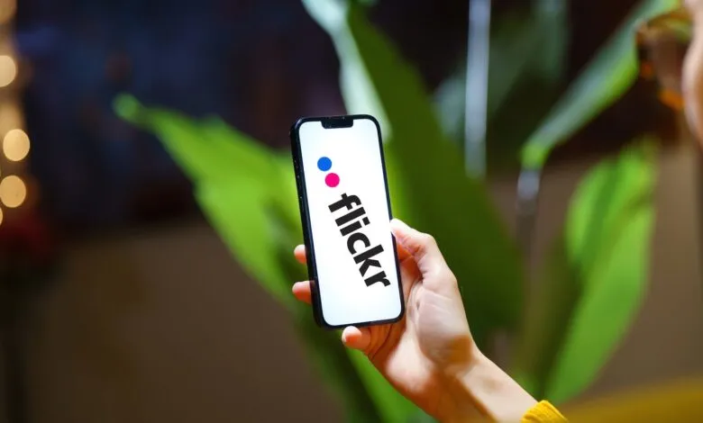 Hand holding smartphone displaying the Flickr logo.