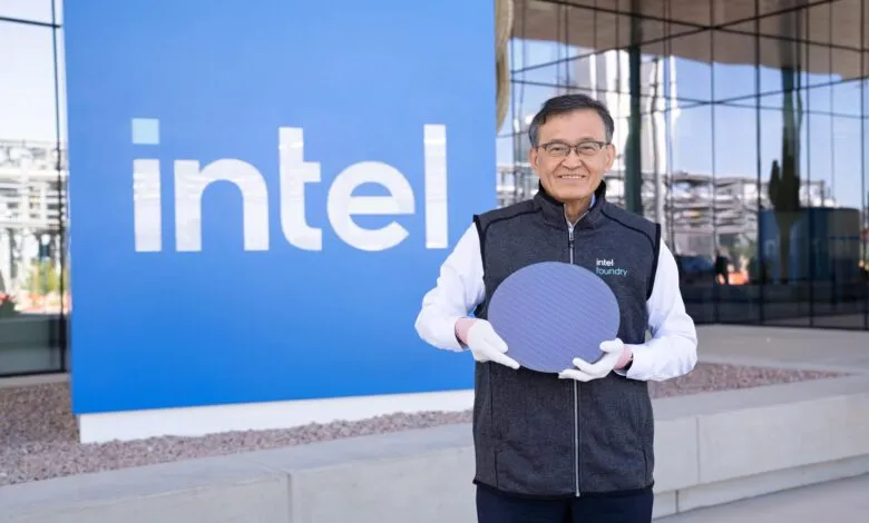 Intel CEO Pat Gelsinger holds silicon wafer in front of Intel sign.