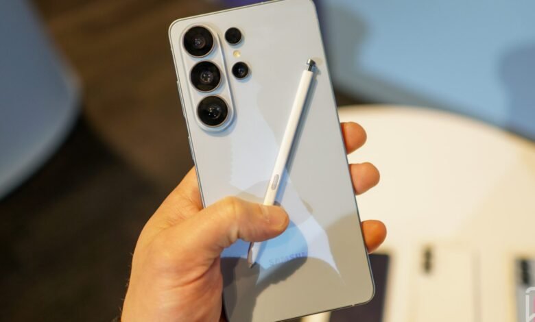 Hand holding a light blue Samsung Galaxy phone with stylus.