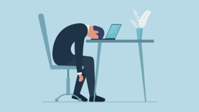 Cartoon of exhausted person slumped over laptop at desk.