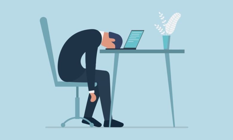 Cartoon of exhausted person slumped over laptop at desk.