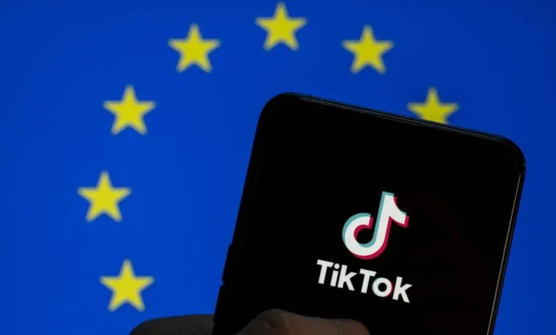 TikTok logo on phone screen against EU flag backdrop.