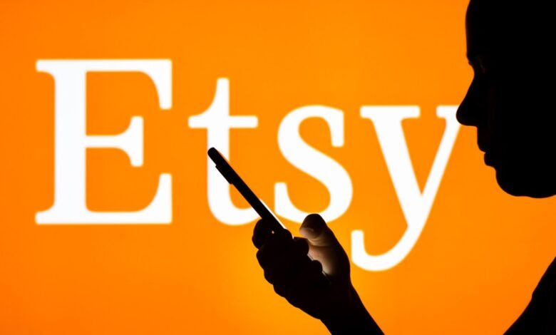 Silhouette of person using phone with Etsy logo in background.