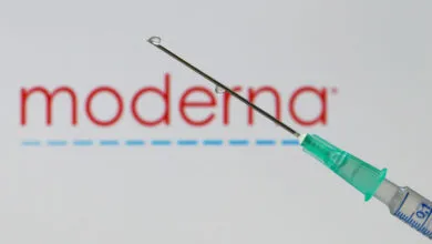 Syringe with droplet against Moderna logo, vaccine concept.