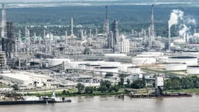 Aerial view of a large industrial oil refinery complex with storage tanks and river.