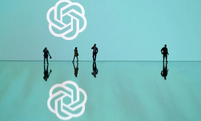 Miniature figures stand before a large screen displaying the OpenAI logo.