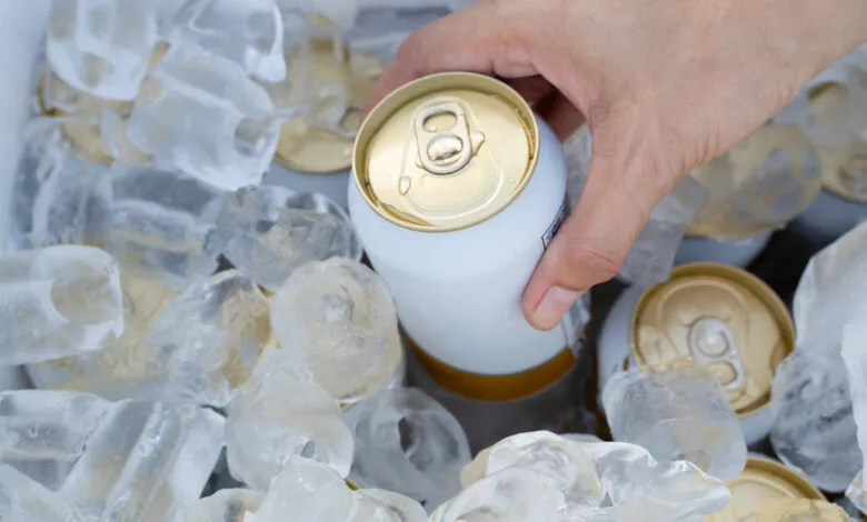 Hand reaches into cooler filled with ice to grab a cold can.