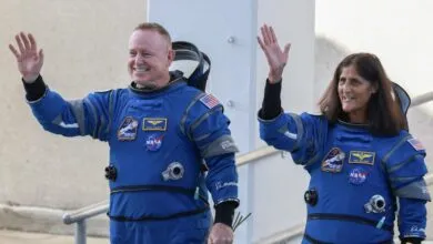 Astronauts Butch Wilmore and Suni Williams wave in their blue Boeing spacesuits.