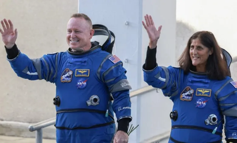 Astronauts Butch Wilmore and Suni Williams wave in their blue Boeing spacesuits.