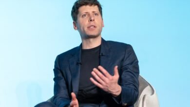 Sam Altman speaks at an event, wearing a suit and gesturing.