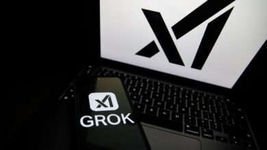 Phone displaying the Grok logo sits on a laptop with the X logo on the screen.
