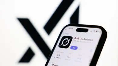 Smartphone displaying Grok AI Assistant app against blurred X logo.
