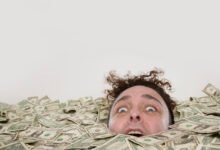 Man's head emerges from pile of American dollar bills.