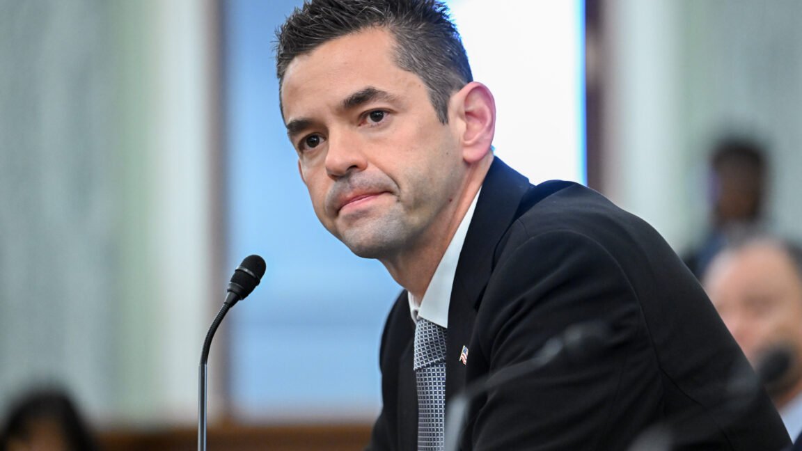 Jared Isaacman at Senate hearing, wearing suit and tie, microphone visible.