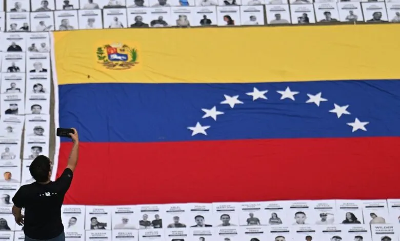 Person takes photo of Venezuelan flag surrounded by portraits.