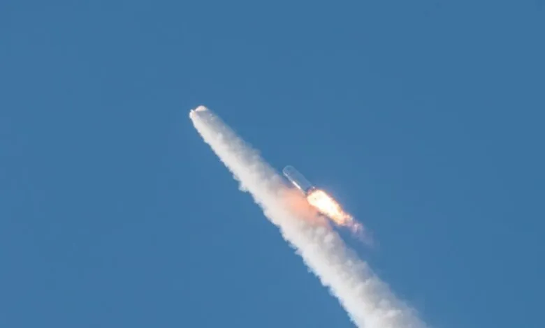 Long March-10 rocket ascends, leaving a trail of white smoke against a blue sky.