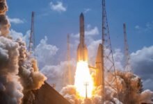 Rocket launching with bright flames and smoke against a blue sky with clouds.