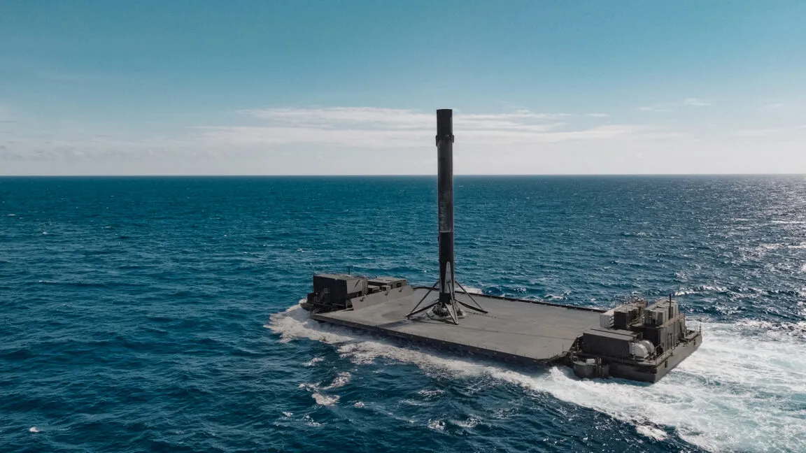 SpaceX Falcon 9 rocket booster on drone ship in the ocean.