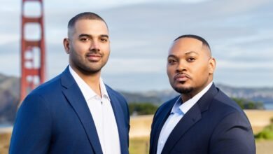 Two men in suits stand before the Golden Gate Bridge, smiling confidently.