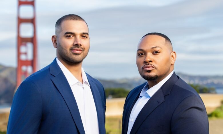 Two men in suits stand before the Golden Gate Bridge, smiling confidently.